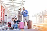 Family with suitcases waiting at train station platform
