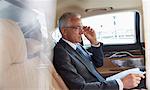 Businessman with paperwork riding in back seat of town car