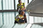 Airport ground crew workers examining airplane in hangar