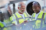 Air traffic control ground crew workers talking using digital tablet on airport tarmac