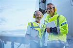 Portrait confident air traffic control ground crew workers with digital tablet near airplane on tarmac