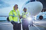 Portrait confident air traffic control ground crew workers near airplane on airport tarmac