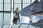 Air traffic control ground crew workers examining corporate jet in airplane hangar