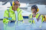 Air traffic control ground crew workers with clipboard talking on airport tarmac