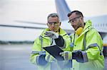 Air traffic control ground crew workers with clipboard talking on airport tarmac