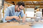 Stained glass artist listening to music with earbuds and working in studio