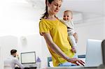 Mother holding baby daughter at laptop