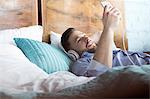 Man listening to music with headphones and mp3 player laying on bed