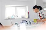 Businesswoman drinking coffee and working at laptop in office