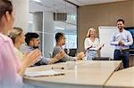 Business people clapping for businessman in conference room meeting