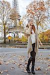 Autumn getaways in Paris. Full length portrait of happy young woman in Paris, France using a mobile phone