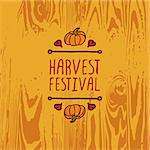 Hand-sketched typographic element with pumpkin, maple leaves and text on wooden background. Harvest festival