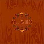 Hand-sketched typographic element with mushroom, berries and text on wooden background. Fall is here