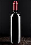 Bottle of red wine dark glass on wooden bacground red top