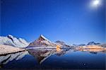 Full moon and stars light up the snow capped peaks reflected in sea, Volanstinden, Fredvang, Lofoten Islands, Northern Norway, Scandinavia, Europe