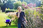 Female gardener at Waterperry Gardens in Oxfordshire, using a mobile phone.