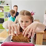 A family making breakfast. A child taking a slice of bread out of the toaster.