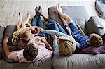 A family at home.  View from above of two adults and two children seated on a sofa together.