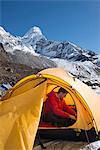 A mountaineer packs his bag in preparation to climb Ama Dablam, the 6856m peak in the distance, Khumbu Region, Himalayas, Nepal, Asia