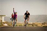 Three mature cyclists on the road looking victorious