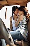 Lesbian couple kissing in a retro pick-up truck.