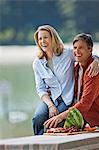 Happy middle aged couple enjoying a healthy fruit picnic in the park.