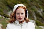 Young redhead woman in hooded shirt looking at camera