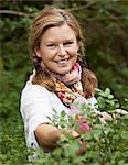 Woman picking blueberries, smiling, portrait