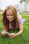 Portrait of woman lying on grass and using mobile phone