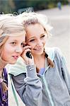 Two girls, one using mobile phone