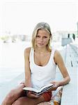 Young woman holding book, smiling, portrait