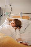 Girl lying on hospital bed with IV drip on arm