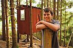 Teenage boy leaning on wooden plank in front of cottage