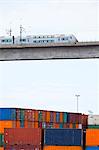 Monorail on elevated bridge over cargo containers