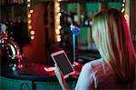 Rear view of waitress using a digital tablet in bar