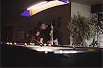 Young happy couple playing pool in bar