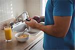 Mid section of man using his mobile phone in the kitchen at home