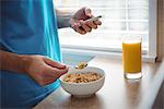 Mid section of man using mobile phone while having breakfast in kitchen at home