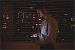 Man using his digital tablet near window blinds at night