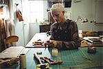 Attentive craftswoman preparing leather belt in workshop