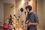 Man singing with a microphone while playing tambourine in music studio