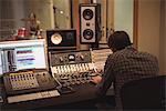 Rear view of audio engineer using sound mixer in recording studio