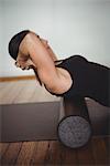 Woman exercising with foam roll in fitness studio