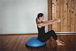 Woman doing exercise on bosu ball in fitness studio