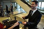 Businessman handing over his boarding pass to the female staff at airport terminal