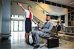 Female staff showing directions to businessman at airport terminal