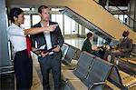 Female staff showing directions to businessman at airport terminal