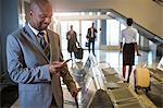 Businessman using mobile phone in waiting area at airport terminal