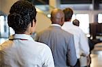 Rear view of female staff and passengers standing in the airport terminal