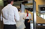 Rear view of woman handing over her boarding pass to the female staff